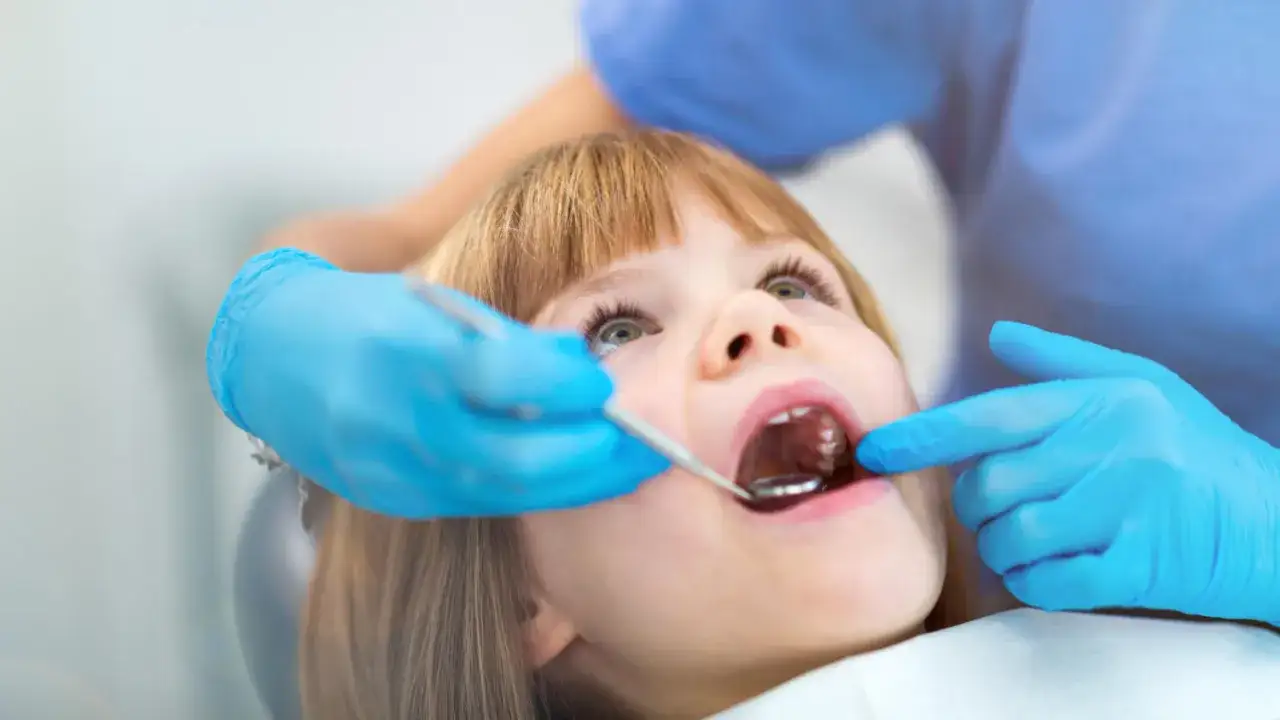 Mała dziewczynka u dentysty. Wypadanie zębów mlecznych u 5 latka to naturalny etap rozwoju.