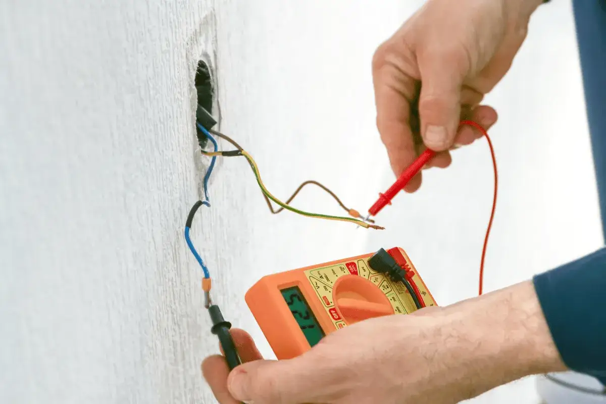 Elektryk wykonuje pomiar rezystancji uziemienia za pomocą multimetru.
