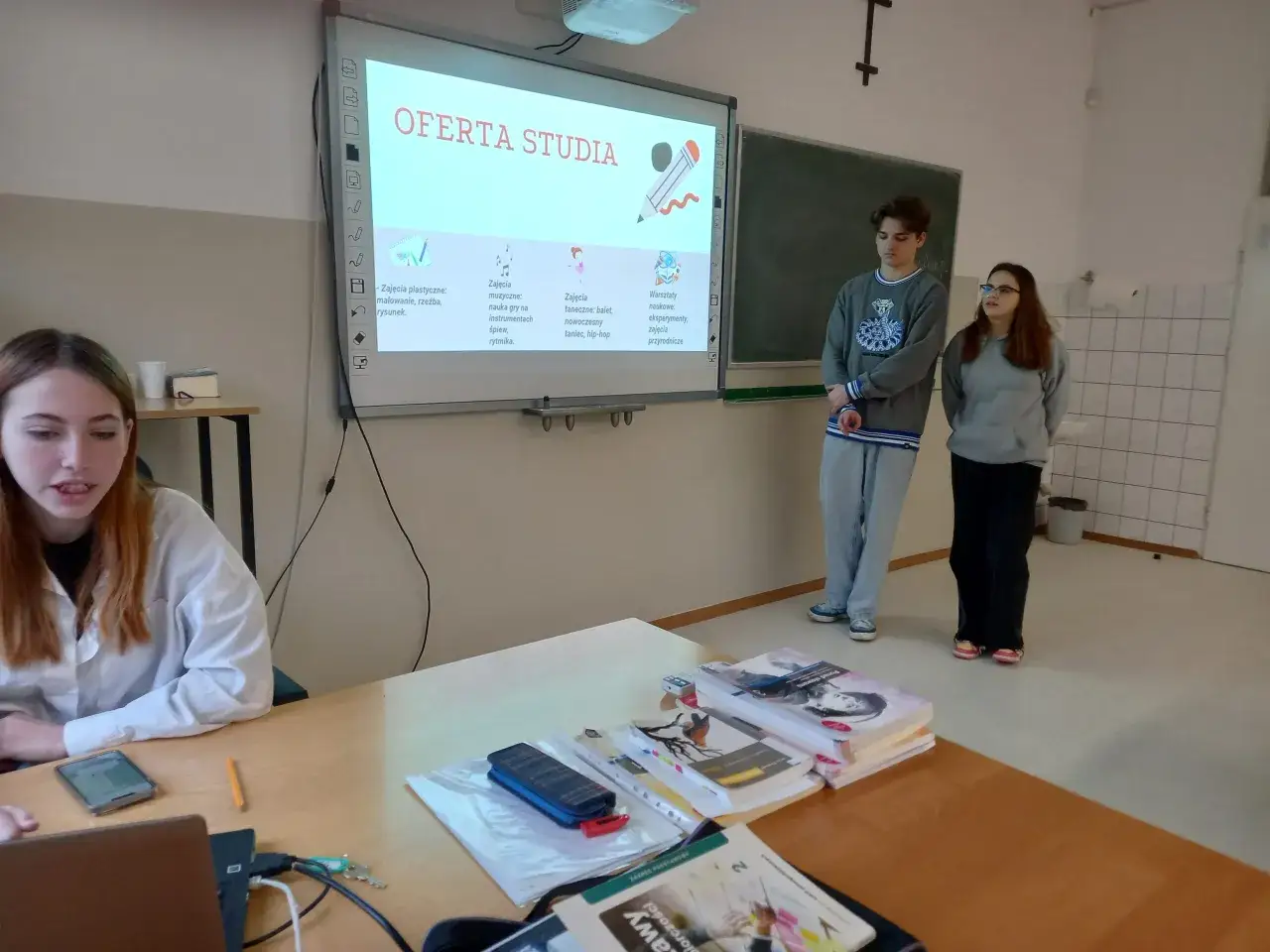 Uczniowie prezentują ofertę zajęć, rozwijając swoją przedsiębiorczość. Na ekranie widnieje napis 