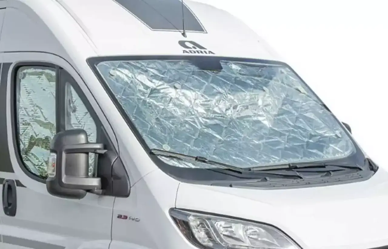 En vit husbil med en reflekterande vindrutet&auml;ckning, som en del av en truma frostvakt manual.