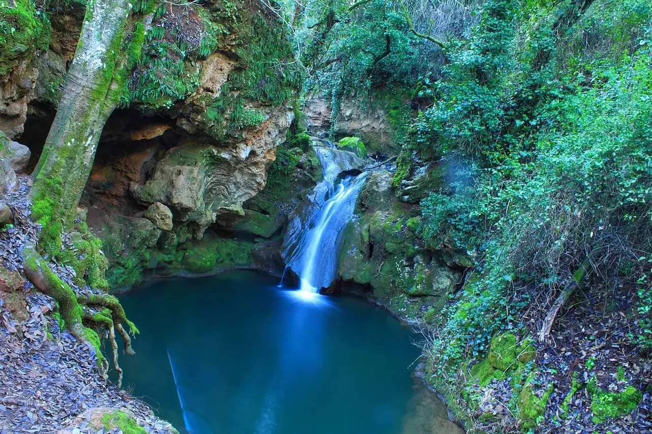 Cascada en la ruta baños de Popea, con agua azul turquesa y vegetación exuberante.