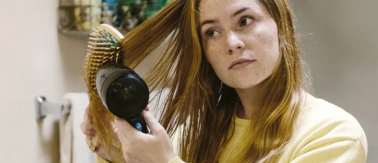Frau föhnt ihr Haar, um fliegende Haare zu bändigen.