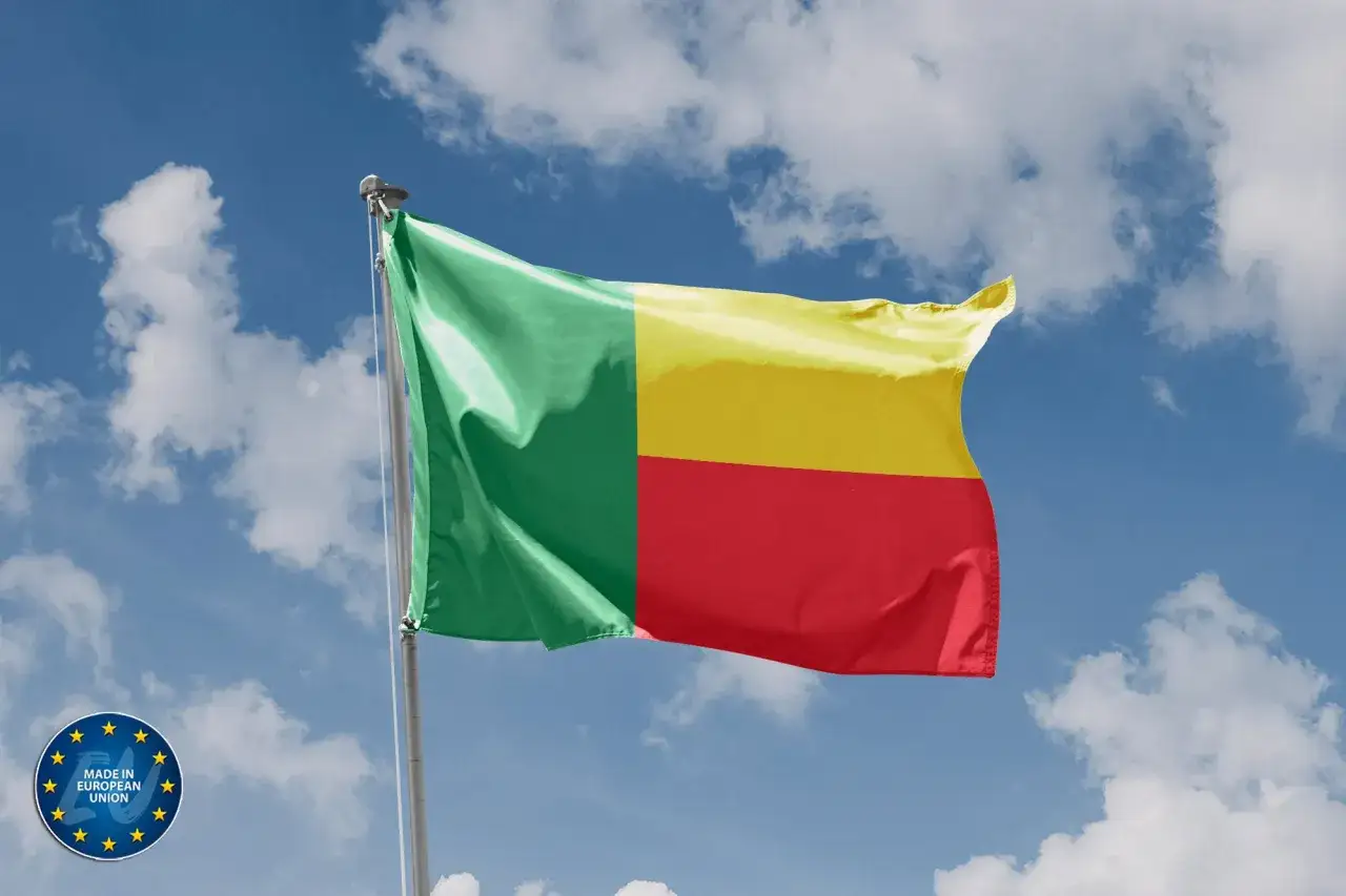 Benin flaga powiewa na tle błękitnego nieba z chmurami.