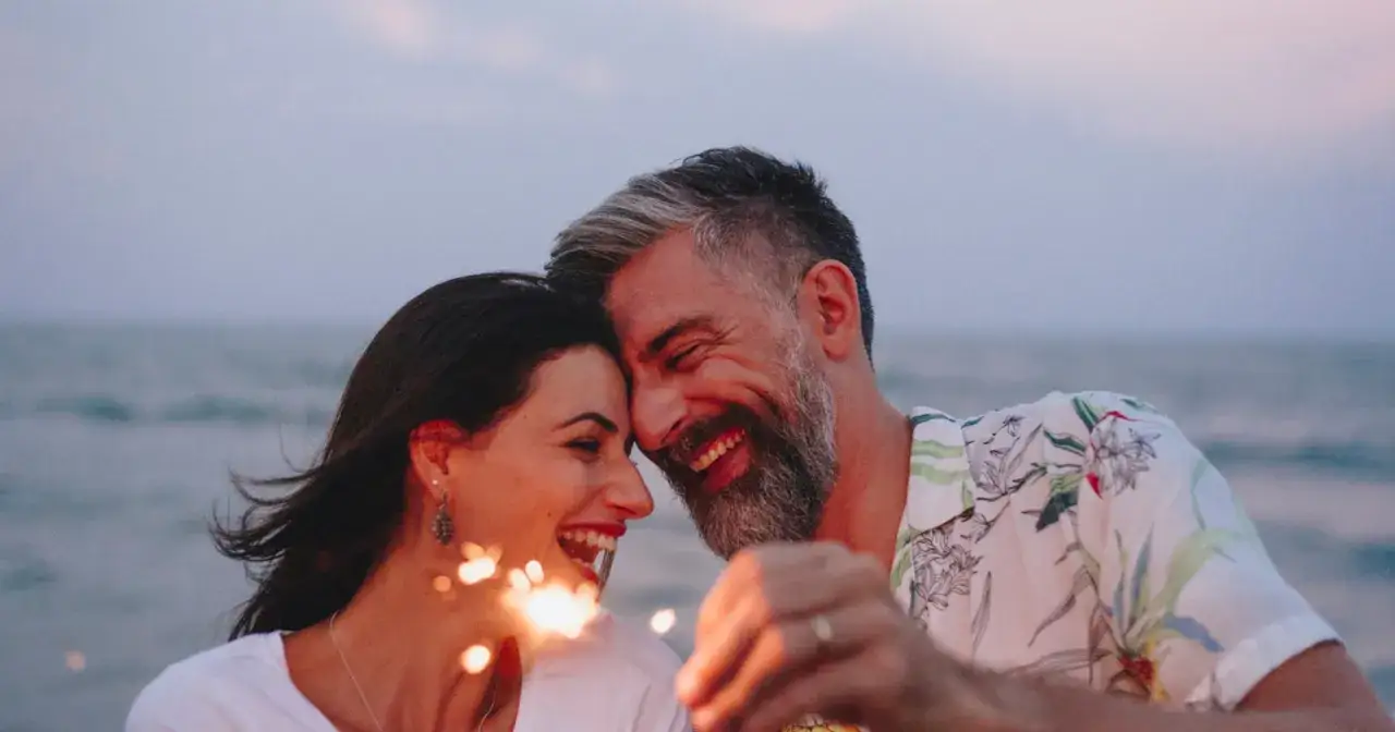 Para świętuje 100 naszych randek DIY przy plaży, trzymając zimne ognie.