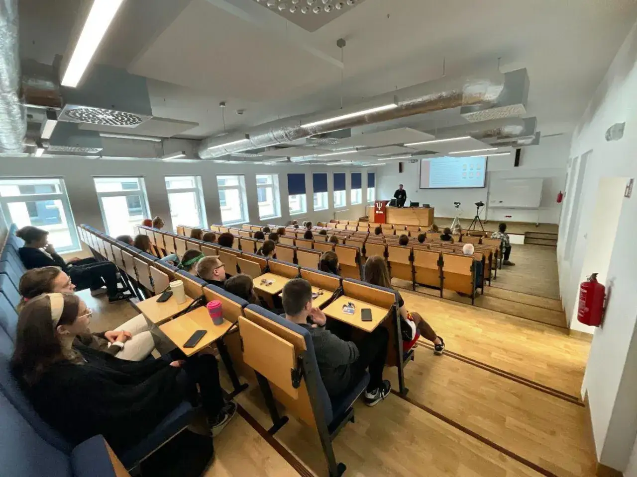 Wykład o tym, co trzeba zrobić, aby zostać psychologiem. Studenci słuchają wykładowcy w auli.