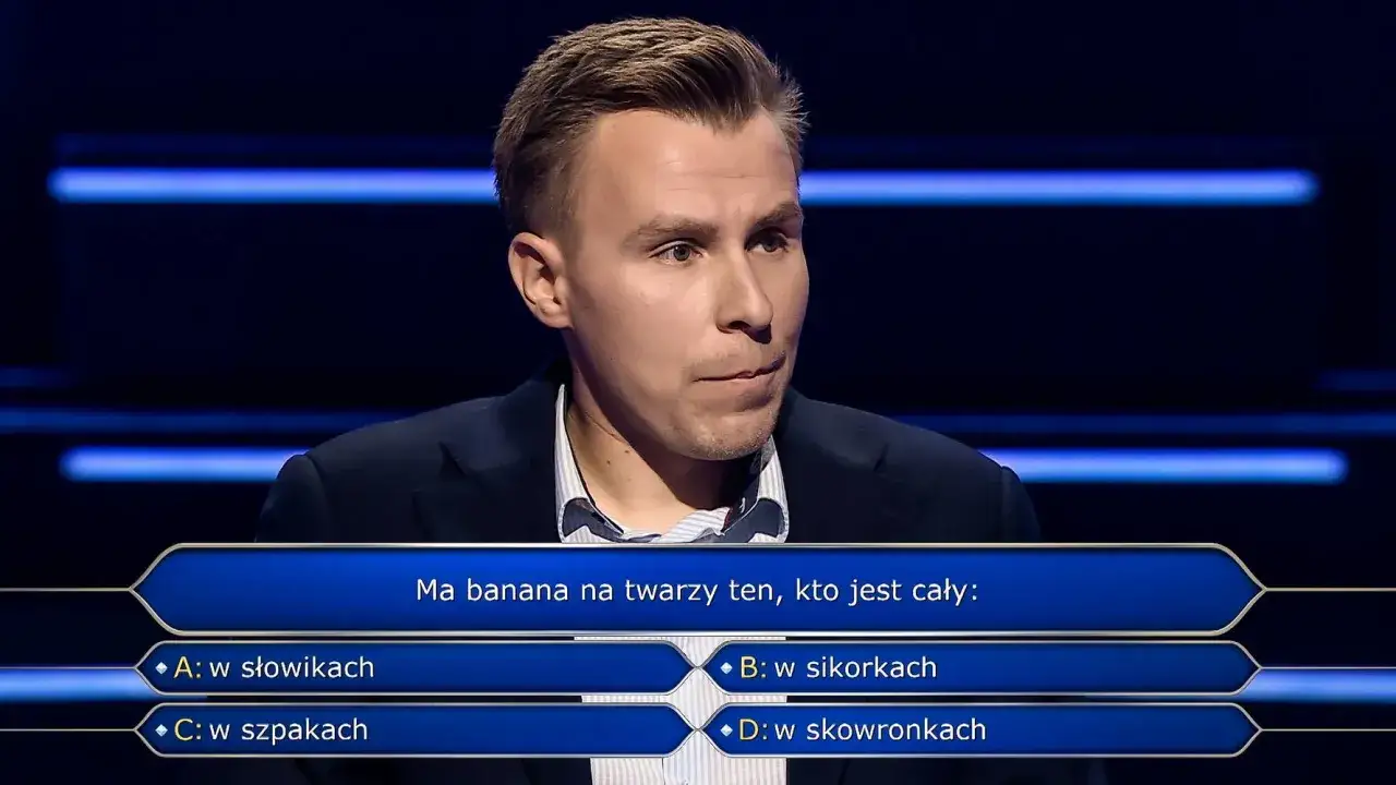 Młody mężczyzna w garniturze zastanawia się nad pytaniem z teleturnieju