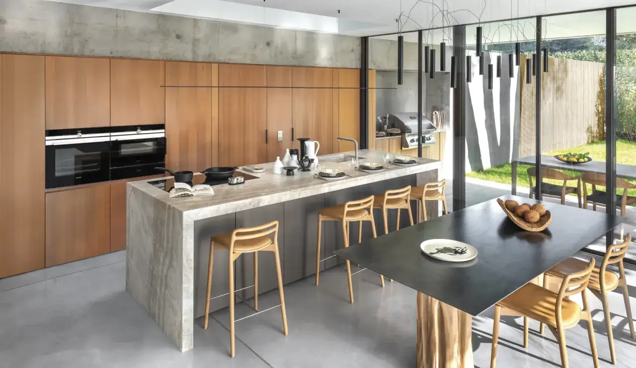 Cuisine moderne avec îlot central en marbre, tabourets en bois et vue sur jardin. Une belle cuisine inspiration pour vos repas.