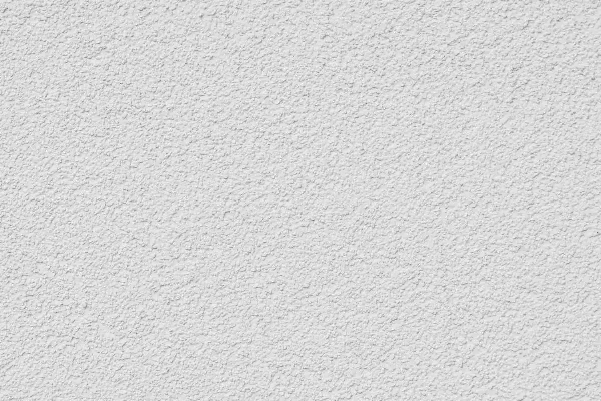 Eine weiße Wand mit einer strukturierten Oberfläche, die das Ergebnis von Rollputz auftragen ist.