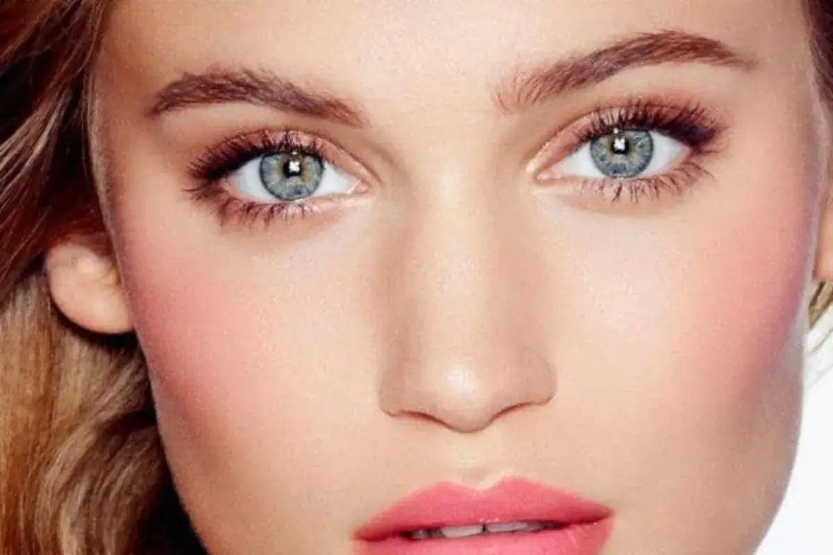 Maquillage subtil pour des yeux bleus d'une blonde, rehauss&eacute;s par un blush ros&eacute; et des l&egrave;vres gourmandes.
