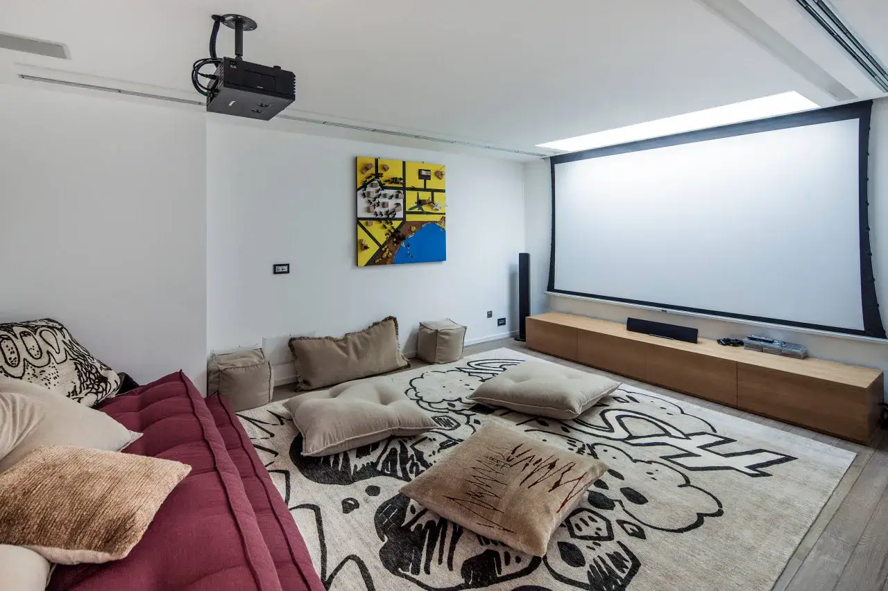 Salle de cin&eacute;ma maison avec vid&eacute;oprojecteur au plafond, &eacute;cran g&eacute;ant, canap&eacute; confortable et tapis graphique. Id&eacute;al pour savoir comment choisir un vid&eacute;oprojecteur.