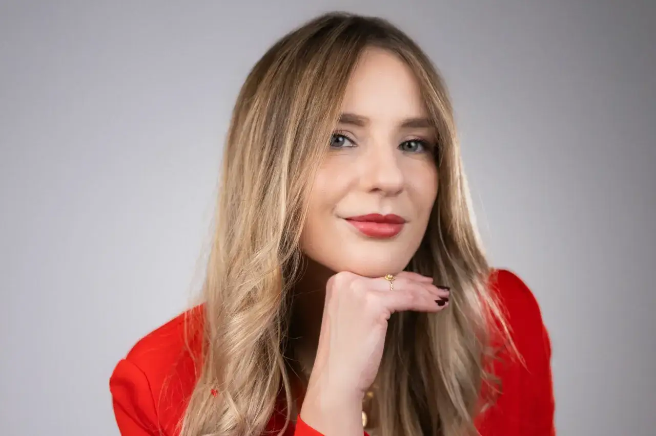 Francesca Florio, con un tailleur rosso, appoggia il mento sulla mano, un anello d'oro al dito.