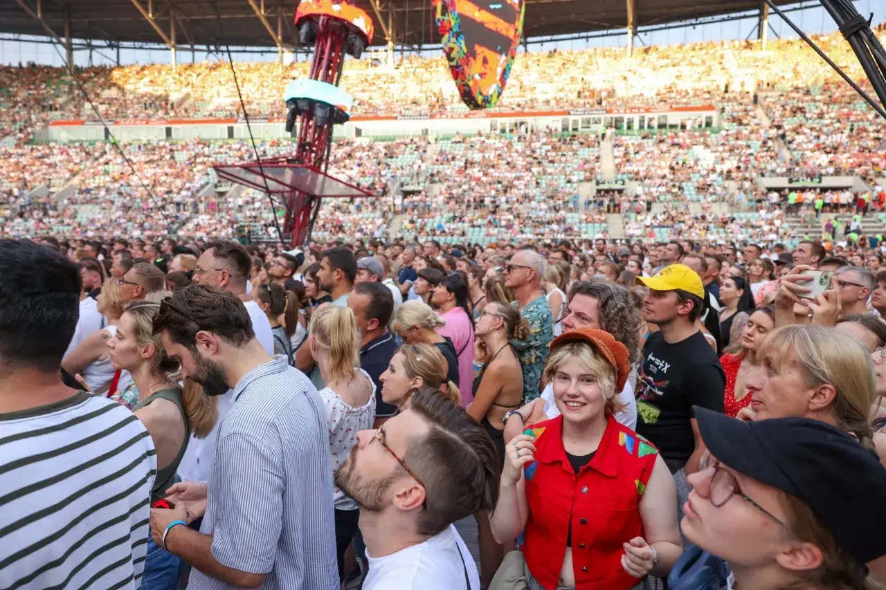 Tłum na koncercie w Polsce, ludzie czekają na występ.