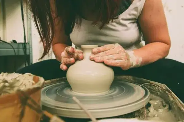 osoba lepiąca naczynie z gliny na warsztatach ceramicznych