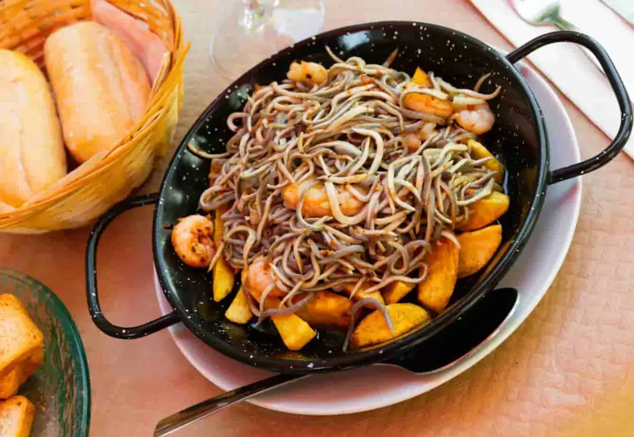 Delicioso plato de angulas congeladas salteadas con gambas y patatas.