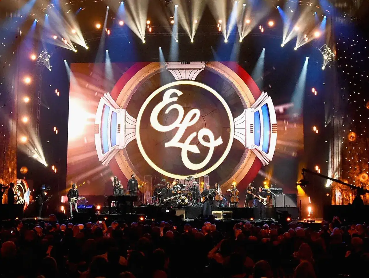 Koncert Electric Light Orchestra, gdzie zespół gra największe przeboje na tle ogromnego logo ELO.