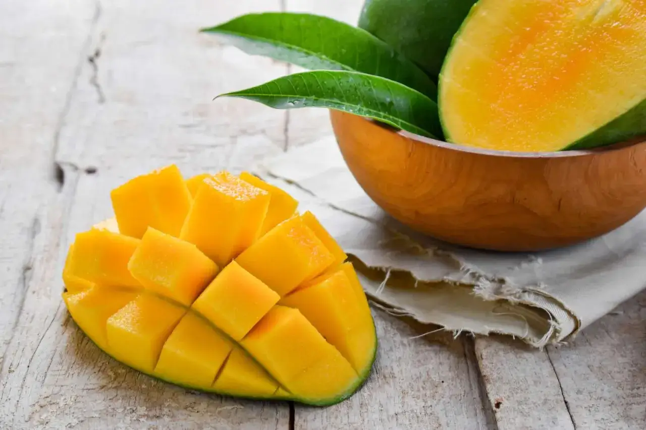 Soczyste mango pokrojone w kostkę, w misce i obok. Warto sprawdzić mango indeks glikemiczny przed spożyciem.