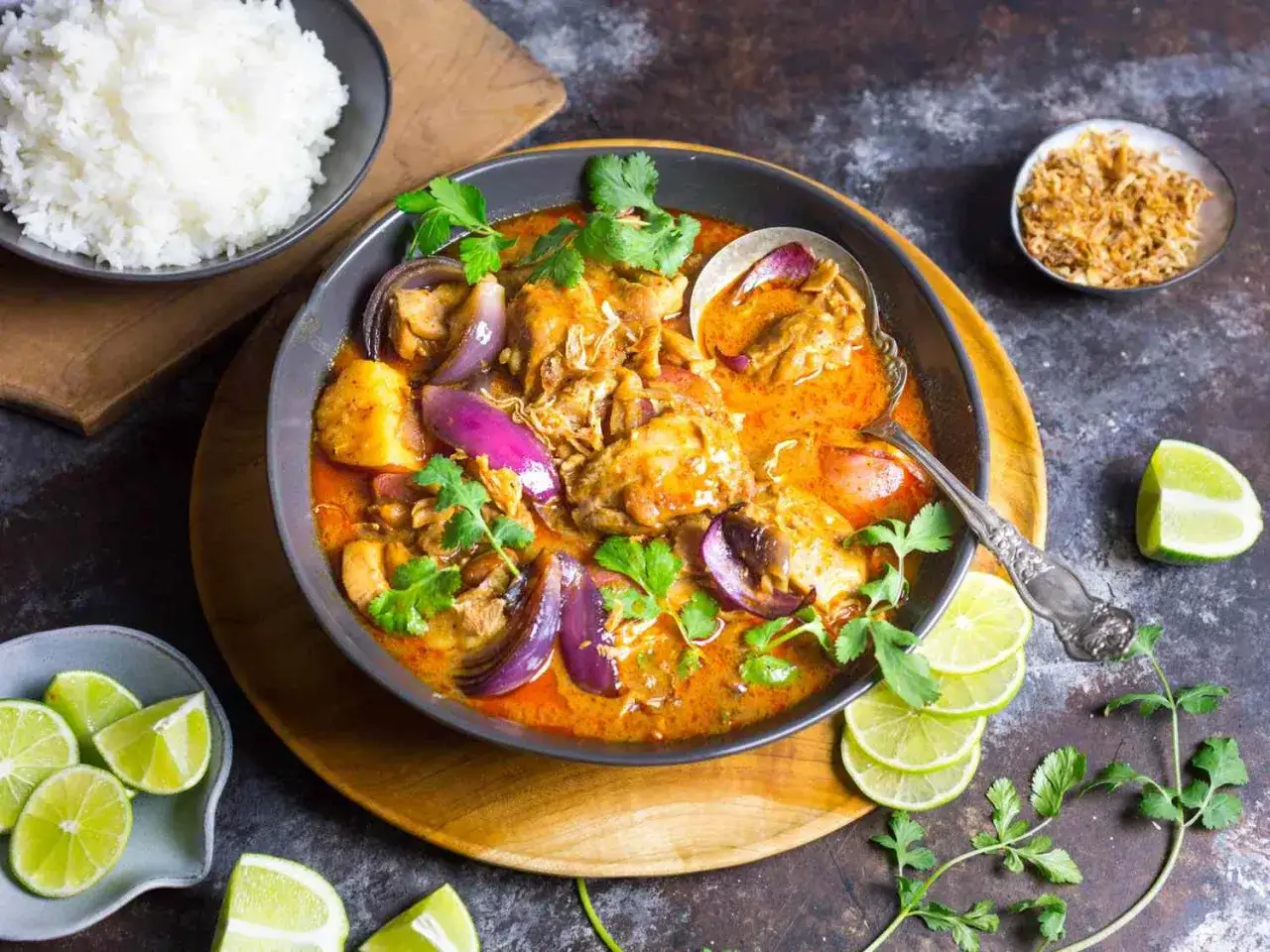 Aromatyczny massaman curry przepis z kurczakiem, ziemniakami i czerwoną cebulą. Podany z ryżem, limonką i kolendrą.