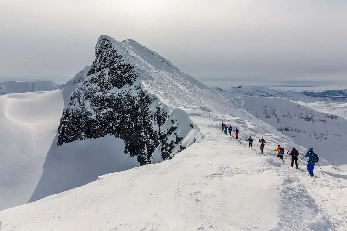 Grupp p&aring; tur mot Sylarnas toppar, en m&auml;ktig sn&ouml;kl&auml;dd bergskam med dramatiska klippformationer.