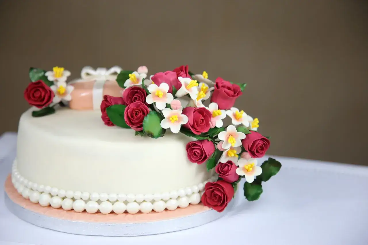 Elegancki tort udekorowany masą cukrową, różami i perełkami. Idealny na specjalne okazje, kiedy udekorować tort jest najważniejsze.