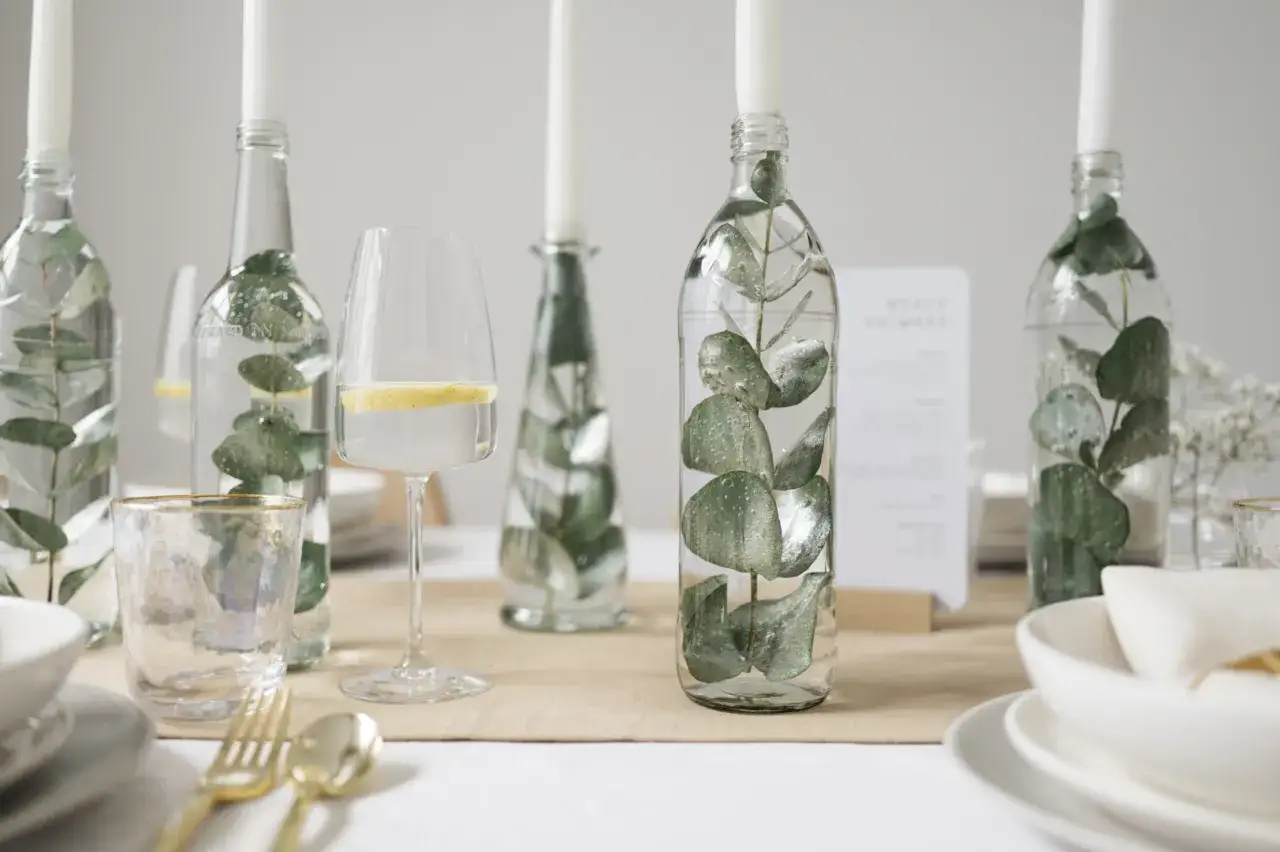Eukalyptus-Zweige in Flaschen als Kerzenhalter und Wassergläser mit Zitronenscheiben – eine stilvolle Idee für eine low budget hochzeit.