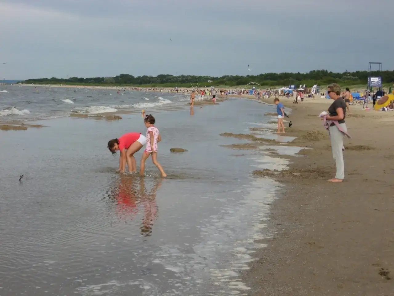 Dzieci bawią się w płytkiej wodzie na plaży. Może to być miejsce, gdzie jest najcieplejsza woda w Bałtyku.
