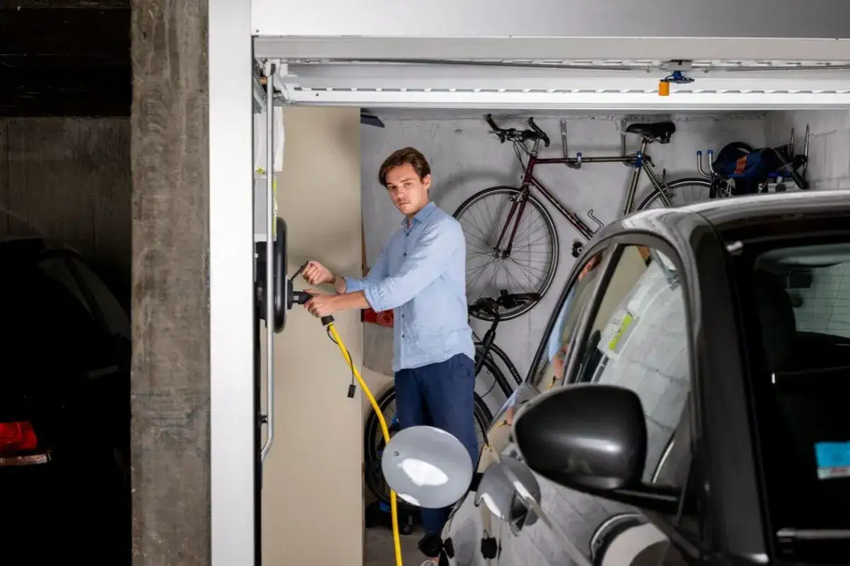 Un homme branche sa voiture électrique à une borne de recharge. La loi LOM encourage l'installation de bornes de recharge pour les véhicules propres.