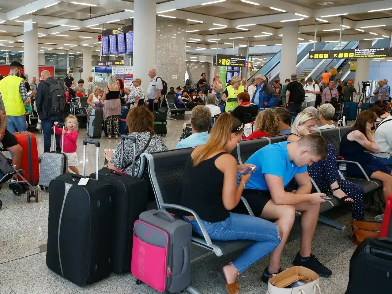 Ludzie z bagażami czekają na lotnisku, być może z powodu strajk&oacute;w na lotniskach.