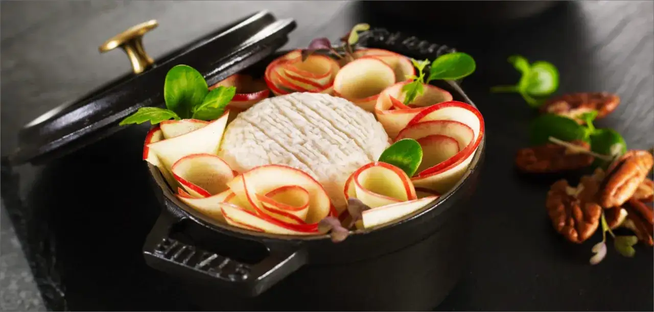 Mini cocotte avec fromage et pommes enroul&eacute;es, une id&eacute;e pour des recettes mini cocottes entr&eacute;es originales. Noix en arri&egrave;re-plan.