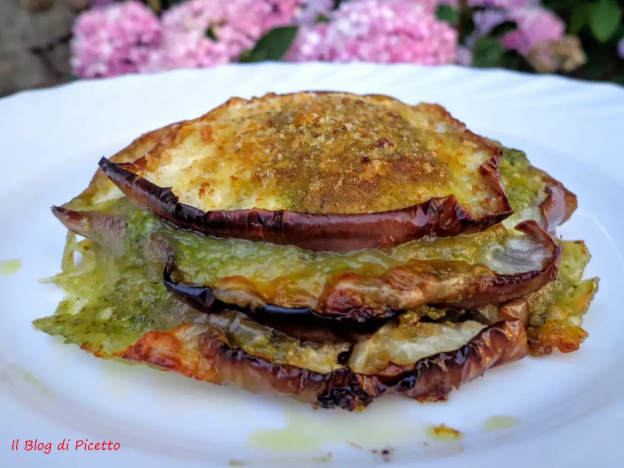 Tramezzini con melanzane grigliate, pesto e formaggio fuso, un'esplosione di sapori mediterranei su un piatto bianco.