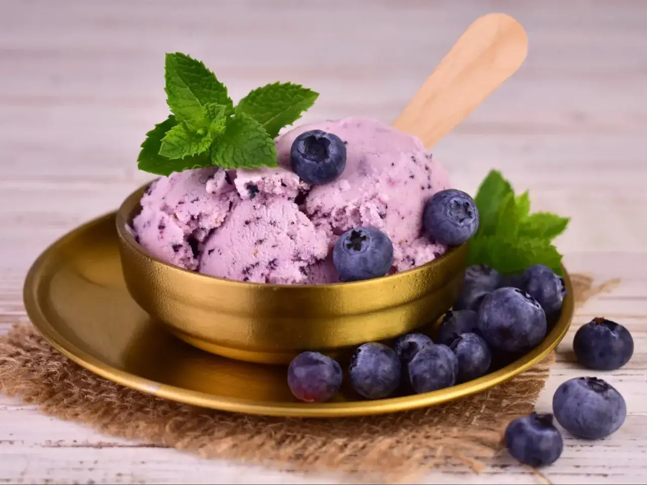 Pyszne domowe lody jagodowe z miętą i świeżymi owocami.
