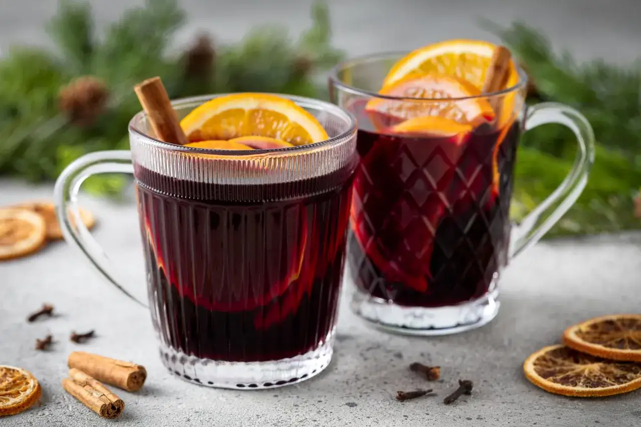 Due tazze di vino per vin brulé, con arancia e cannella, pronte per scaldare le serate invernali.