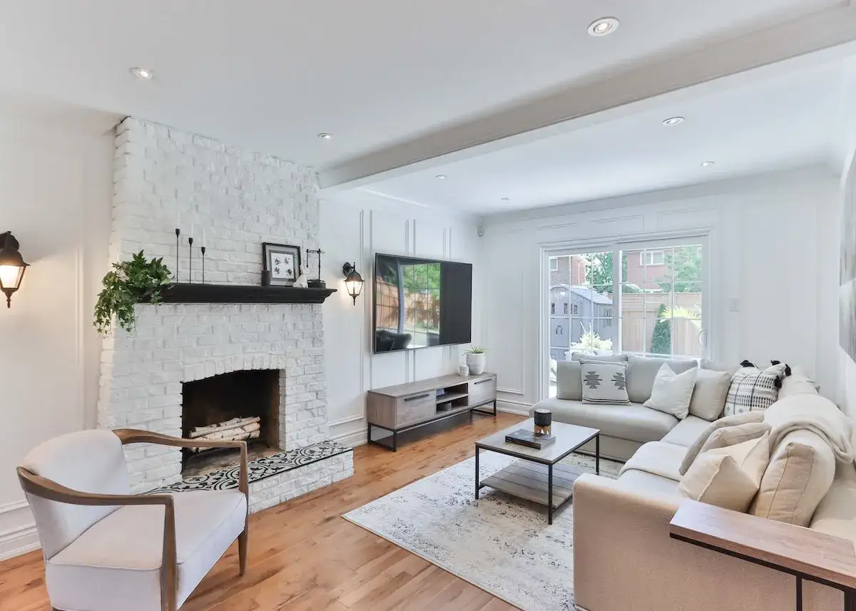 Avant après : relooker une cheminée en brique blanche avec un manteau noir, un fauteuil confortable et un salon moderne.