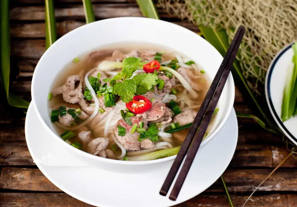 Aromaticzne pho przepis: miska parującego bulionu z wołowiną, makaronem ryżowym, szczypiorkiem i chili.