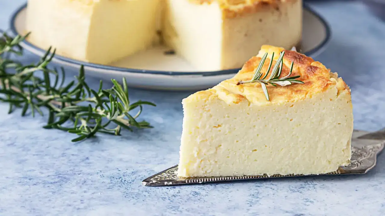 Una fetta di ricotta al forno, dorata e soffice, guarnita con rosmarino fresco.