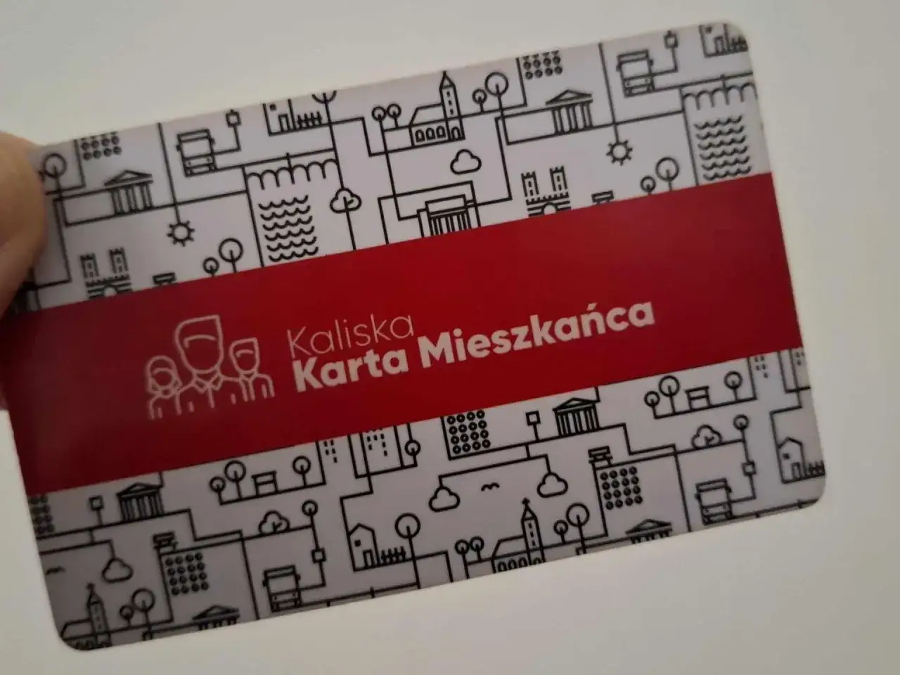 Karta Mieszkańca Kaliskiej - klucz do darmowej komunikacji miejskiej. Na karcie grafika z budynkami i symbolami miasta.