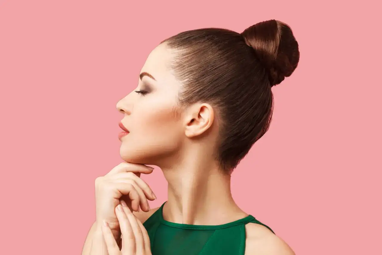 Perfil de mujer con un elegante moño alto, ojos cerrados y mano en la barbilla.