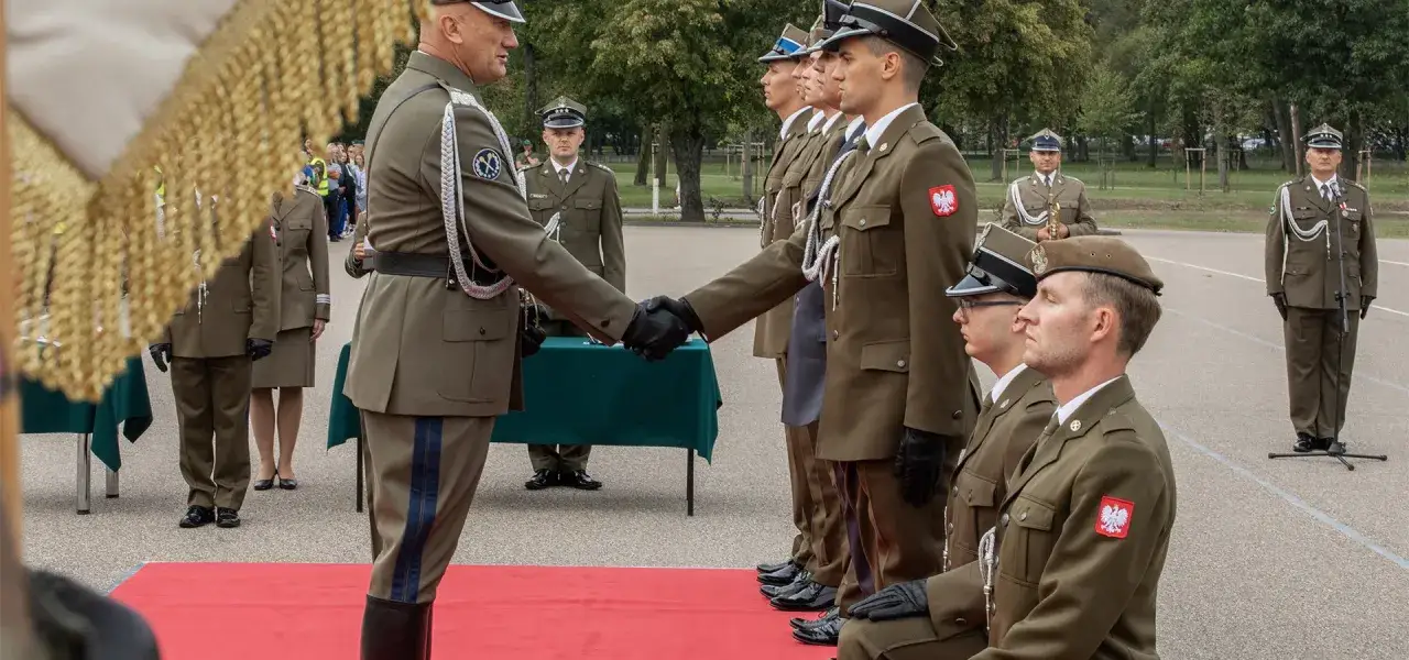 Uroczystość wręczenia odznaczeń. Dow&oacute;dca podaje rękę żołnierzowi, kt&oacute;ry właśnie otrzymał najniższy stopień oficerski.