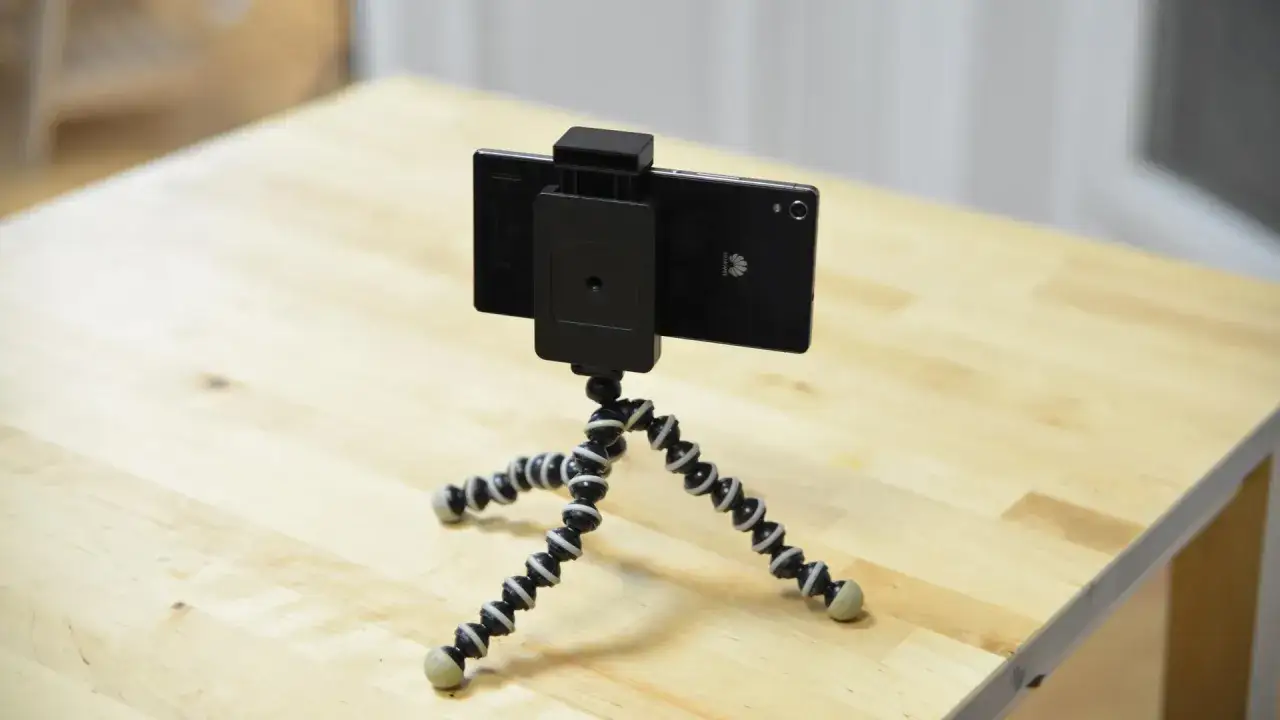 Un smartphone sur un trépied flexible, prêt à surveiller sa maison avec son smartphone gratuit.