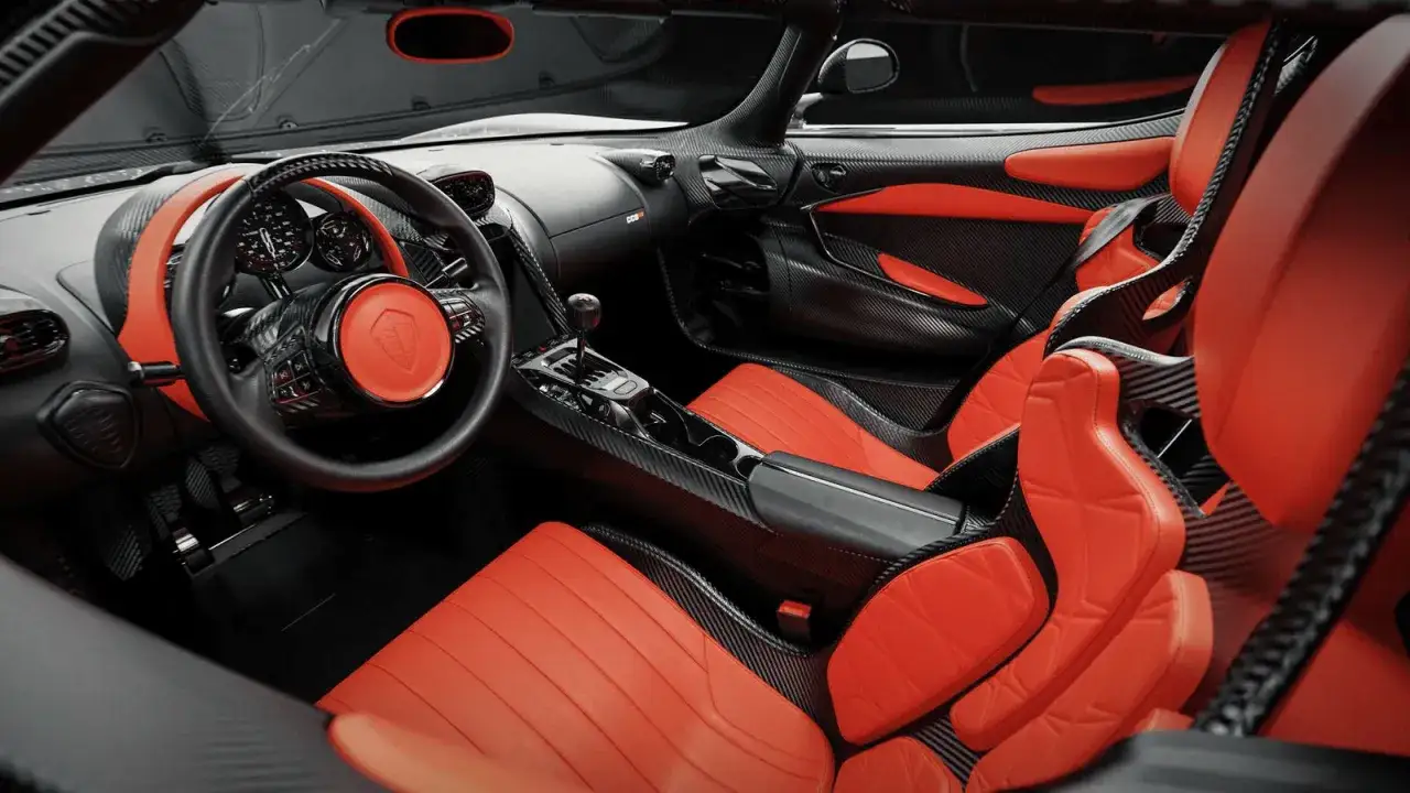 Wnętrze Koenigsegg CC850: sportowe fotele z pomarańczowej skóry i włókna węglowego, kierownica z logo marki.
