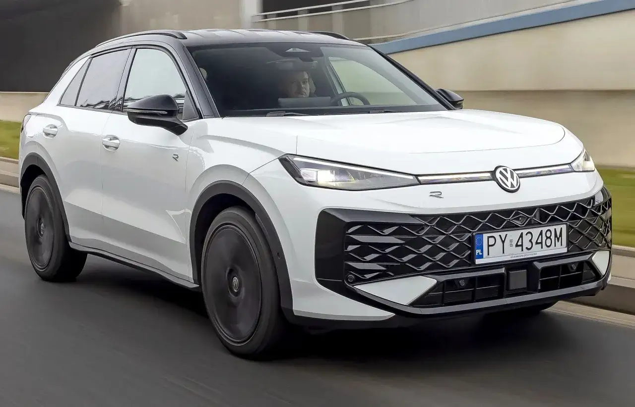 Biały VW T-Roc 2026 z czarnym dachem jedzie po drodze. Kierowca wpatruje się w ekran.