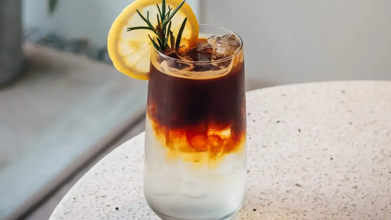 Orzeźwiający tonic espresso z lodem, plasterkiem cytryny i gałązką rozmarynu.