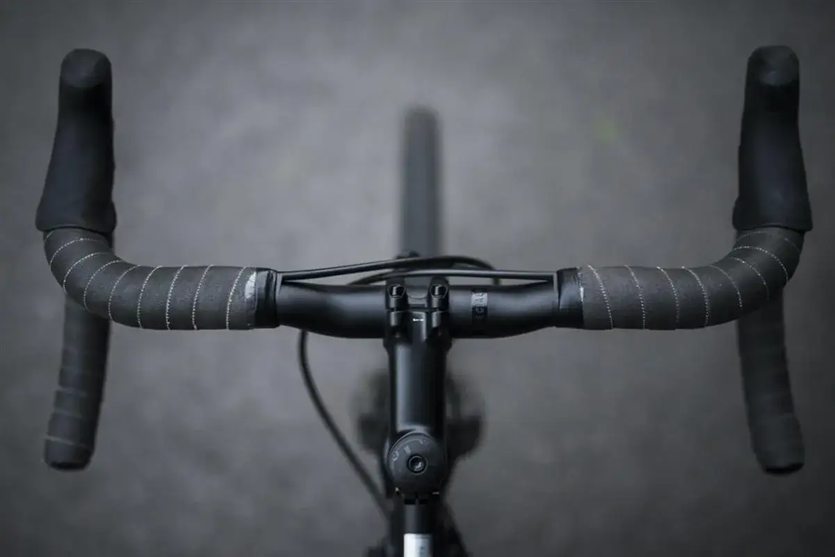 Jak założyć owijkę na kierownicę roweru szosowego? Detal zbliżenia na czarną kierownicę z owijką i manetkami.