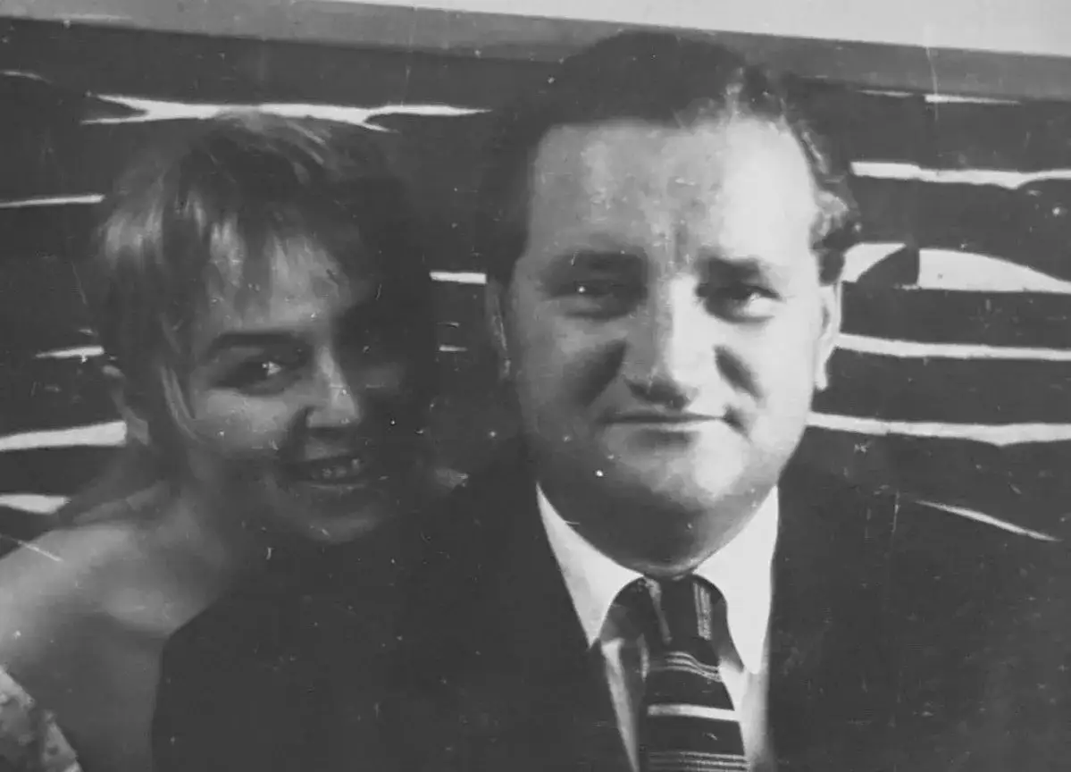 Uśmiechnięta Władysława Nawrocka z mężem, w tle abstrakcyjny wzór.