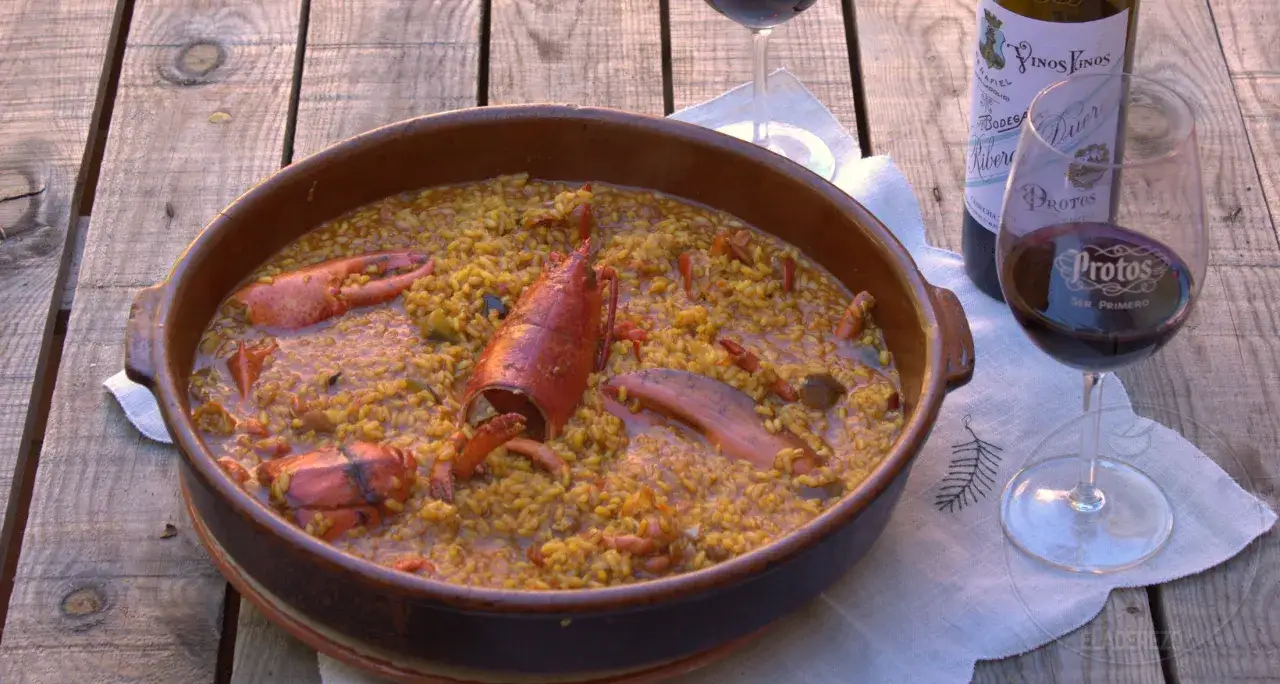 Un delicioso arroz con bogavante en cazuela de barro, acompa&ntilde;ado de vino tinto.