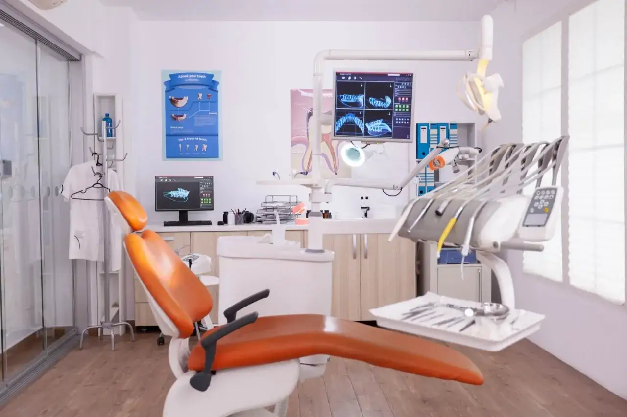 Gabinet dentystyczny gotowy na pierwsza wizyta u dentysty po latach. Pomarańczowy fotel, monitor z RTG zębów i instrumenty czekają.