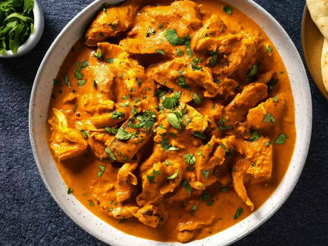Aromaticzny chicken masala w kremowym sosie, posypany świeżą kolendrą, gotowy do podania z chlebkiem naan.