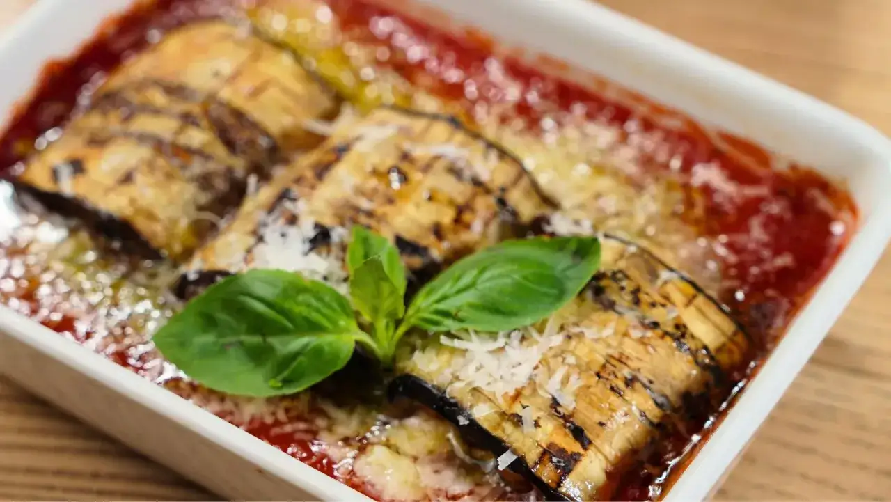 Pastel de berenjenas facilisimo, gratinado con queso y ba&ntilde;ado en salsa de tomate, decorado con hojas de albahaca fresca.