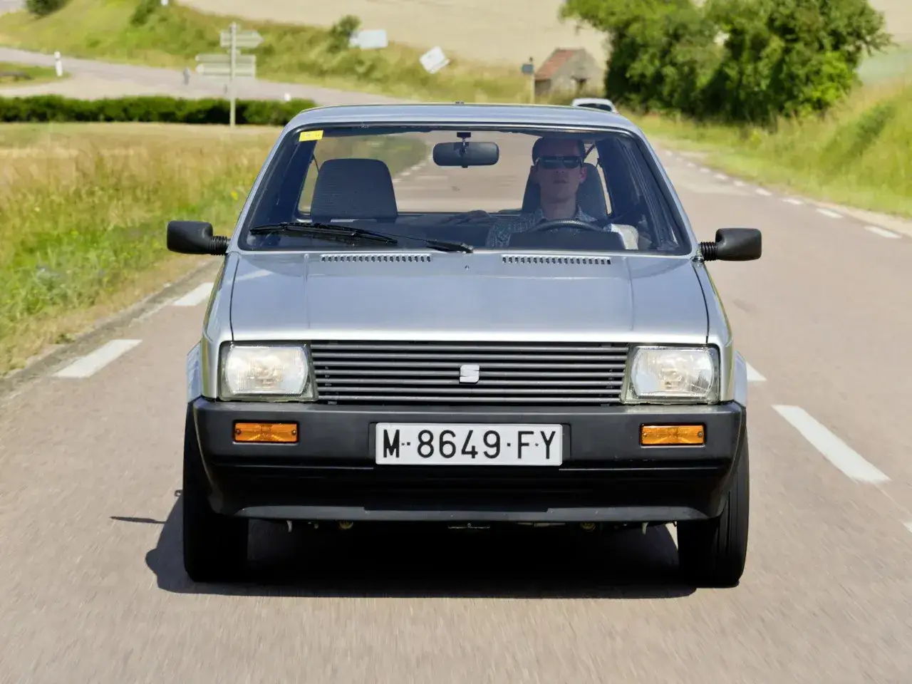 Un hombre conduce un Seat Ibiza 1.2 gasolina por una carretera rural. Opiniones sobre este clásico: ¡fiable y divertido!