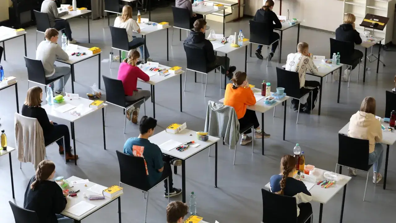 Schülerinnen und Schüler sitzen mit Abstand an Tischen, konzentriert auf ihre Aufgaben. Ein wichtiger Moment für den **Abitur Abschluss**.