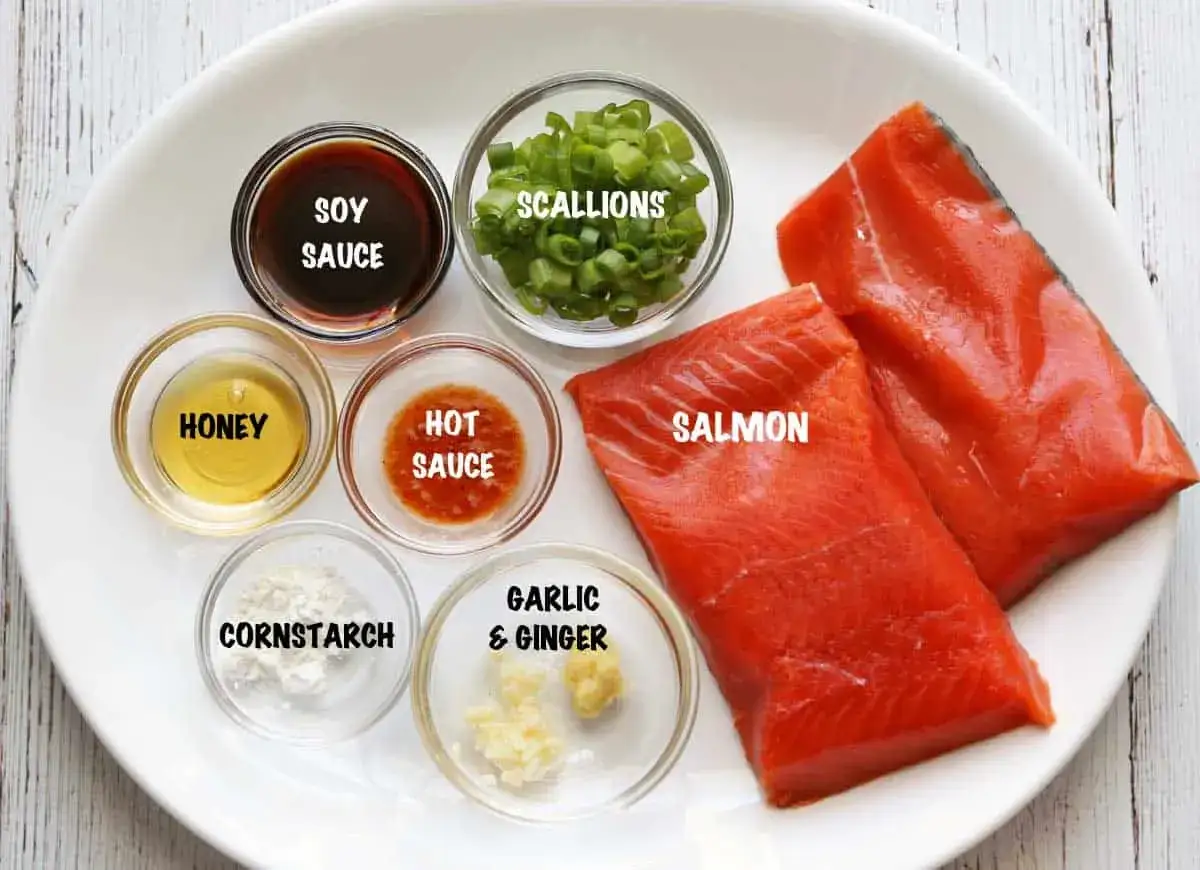 Zutaten für Lachs asiatisch marinieren: Lachsfilets, Sojasauce, Honig, Hot Sauce, Frühlingszwiebeln, Maisstärke, Knoblauch & Ingwer.